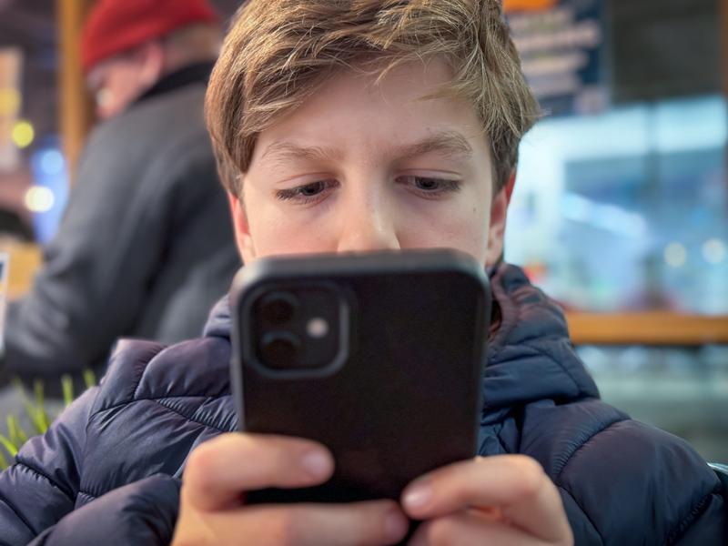 A child looks at an iPhone with a black phone case.