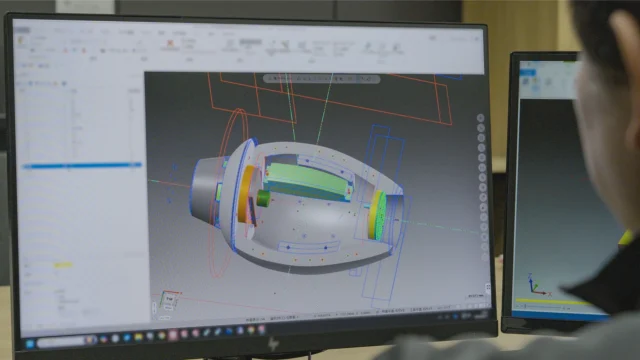 ロックバスターの3D CAD設計画面と作業中のエンジニア