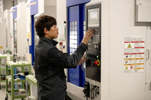 エムズコーポレーションの工場内で、作業者が大型工作機械の操作パネルを操作している様子
