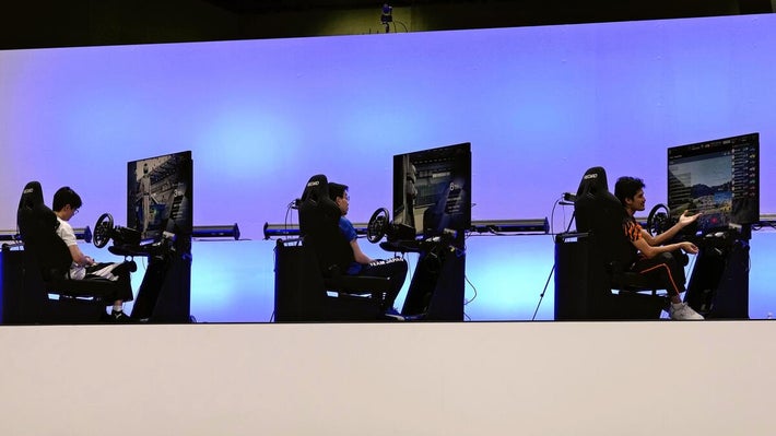 ハンドル型のコントローラーでプレーする選手たち（２３日）＝ＡＰ