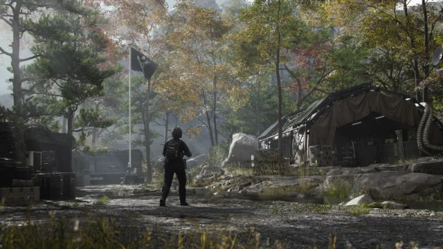 木々に囲まれた野営地で旗の近くに立つ武装した兵士のゲーム画面