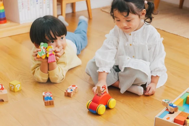 床で二人の子どもがキャラクターのつみきやメロディーカーで遊ぶ様子