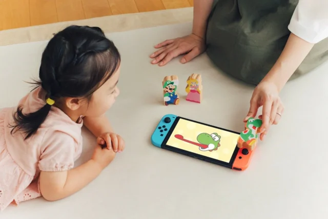 Switch画面のヨッシーとキャラクターのつみきで遊ぶ子ども