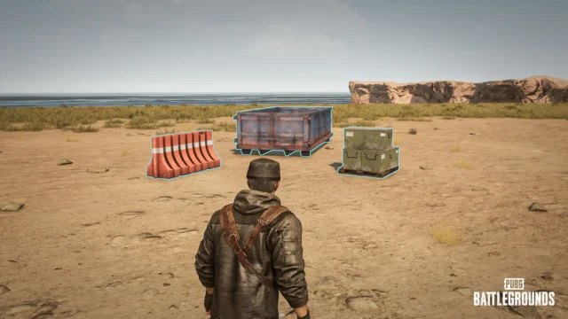 荒野に置かれたバリケード、コンテナ、木箱を見つめるPUBGのキャラクター