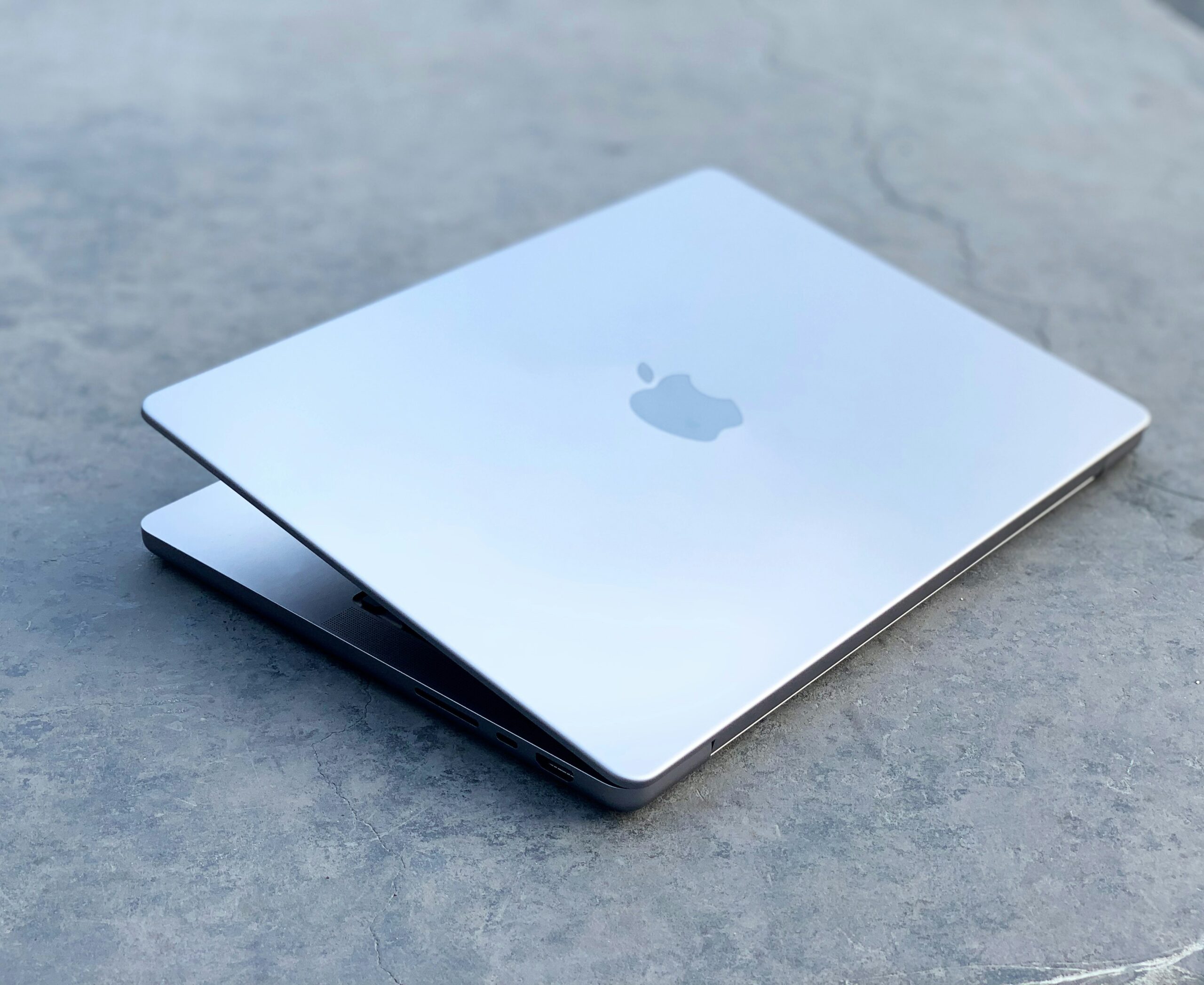 コンクリートの上に置かれた半開きのMacBook。Macのフルディスクアクセスを説明するイメージ