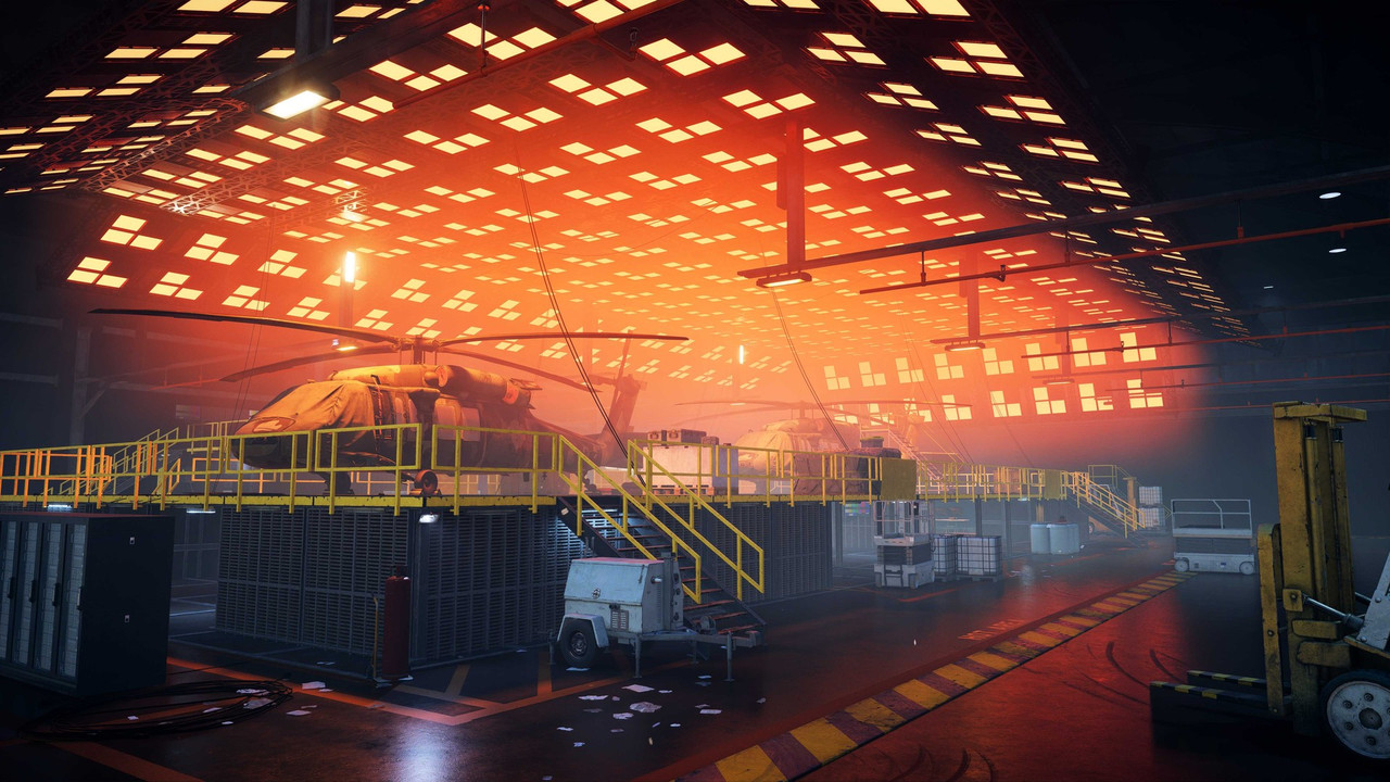 『Battlefield 6』「Area 51」のスクリーンショット。オレンジ色の照明に照らされた格納庫に、カバーを掛けたヘリコプターと黄色い手すりの足場、フォークリフトが並ぶ